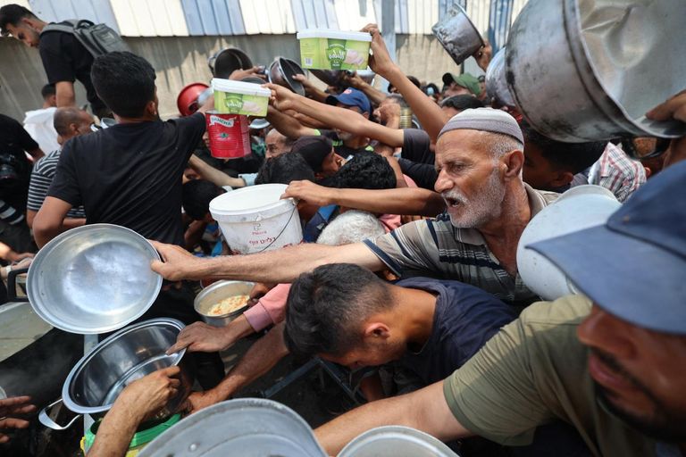 فلسطيني يفحص نفسه بحثًا عن جروح بينما يتصاعد الدخان بعد غارة إسرائيلية