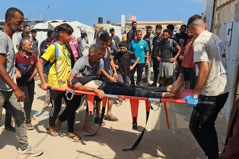 فلسطيني يفحص نفسه بحثًا عن جروح بينما يتصاعد الدخان بعد غارة إسرائيلية