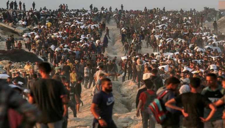 فلسطينيون يحملون أكياس الدقيق على طول شارع الرشيد غرب جباليا