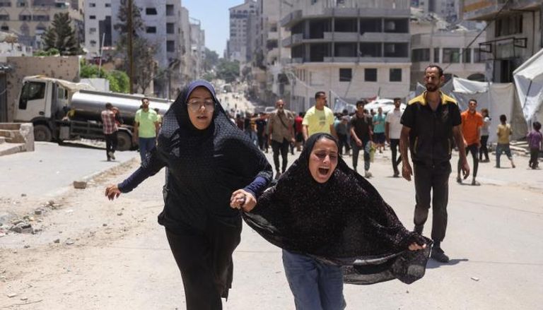 فتاتان تهرولان بأحد الشوارع عقب غارة إسرائيلية