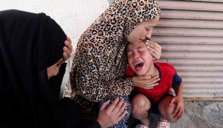 أم تحتضن طفلها أمام مستشفى شهداء الأقصى وسط القطاع