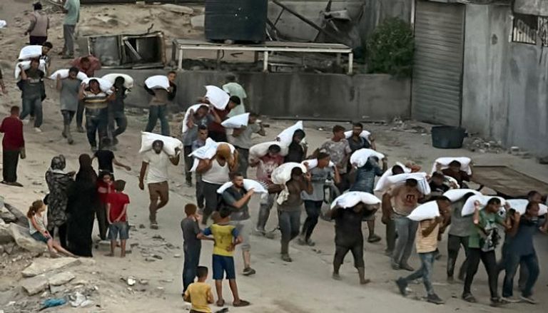 فلسطينيون يحملون أكياس الدقيق في خان يونس