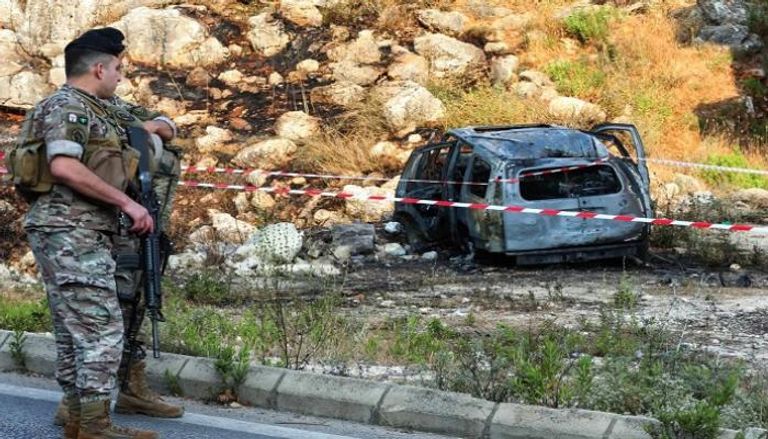 أحد عناصر الجيش اللبناني إلى جانب سيارة استهدفتها مسيرة