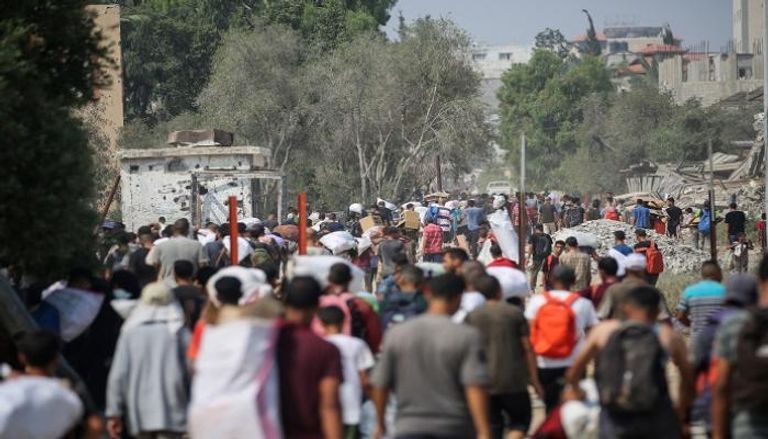 فلسطينيون في مخيم النصيرات يحملون طرودًا غذائية