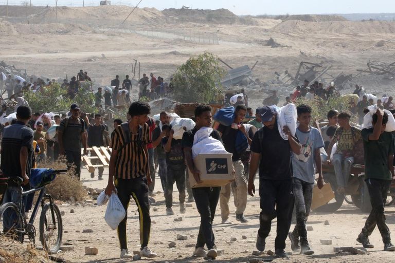 طفل فلسطيني نازح يجلس بجانب قدر من حساء العدس حصل عليه من مركز توزيع