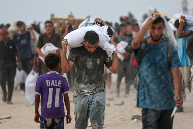 طفل فلسطيني نازح يجلس بجانب قدر من حساء العدس حصل عليه من مركز توزيع