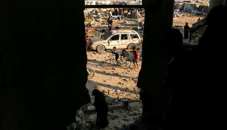 طفل يدفع دراجة قرب سيارة مدمرة في خان يونس