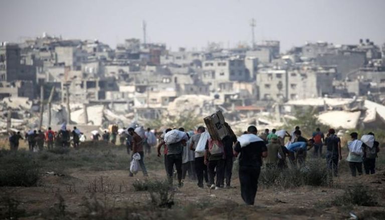 فلسطينيون يحملون أكياسًا وصناديق أثناء عودتهم من نقطة توزيع مساعدات