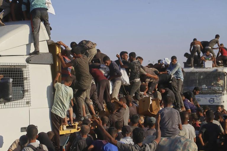 فتاة تقف بجانب جثة شخص قُتل أثناء بحثه عن الطعام بغزة