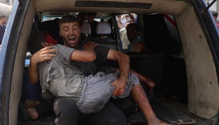 فلسطيني يحمل طفلا مصابا في غزة