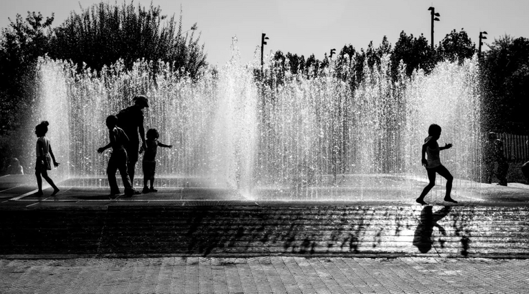 فتاة تغمس رأسها في مياه نافورة قوية للتبريد من حرارة الطقس