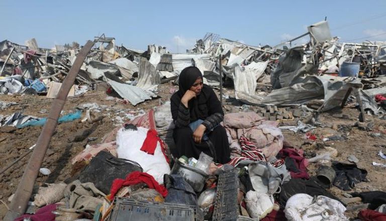 نازحة فلسطينية تجلس على أنقاض مخيم في دير البلح