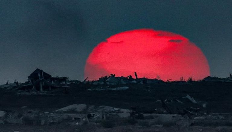 غروب الشمس خلف مبانٍ مُدمّرة في غزة