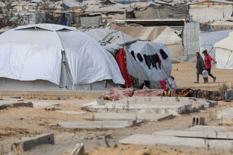 طفل يجلس فوق قبر في خان يونس