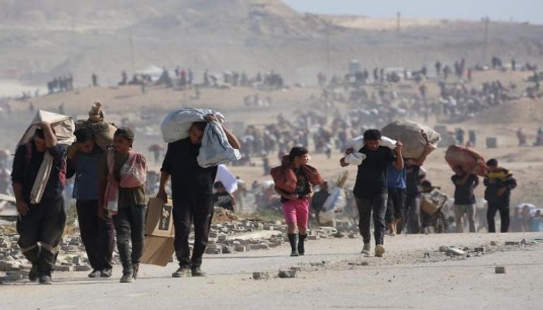 فلسطينيون يحملون أكياسًا من المساعدات الإنسانية قرب ممر نتساريم