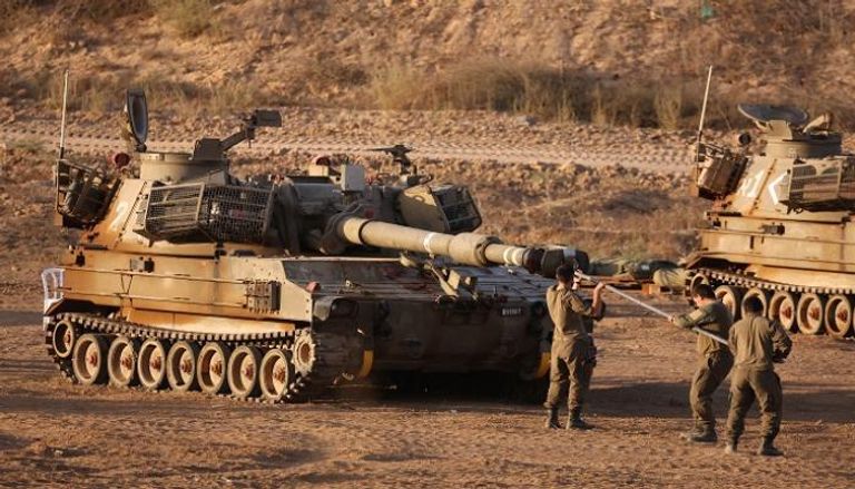جنود إسرائيليون يجهزون مدفع دبابة على حدود قطاع غزة
