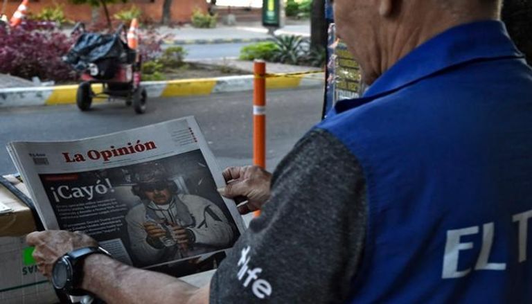 ينظر رجل للصفحة الأولى من صحيفة تحمل صورة للرئيس الفنزويلي مادورو