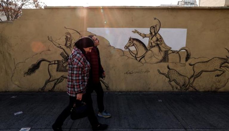 إيرانيون يمرون أمام جدارية في طهران