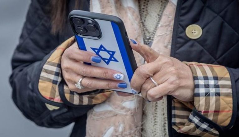 إسرائيلية تمسك هاتفا بيديها