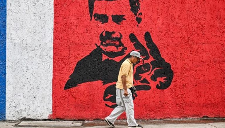 رجل يسير أمام جدارية للرئيس الفنزويلي المخلوع نيكولاس مادورو في كاراكاس