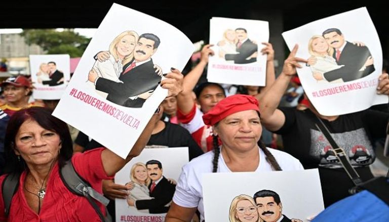 متظاهرون في فنزويلا يرفعون صور نيكولاس مادورو وزوجته