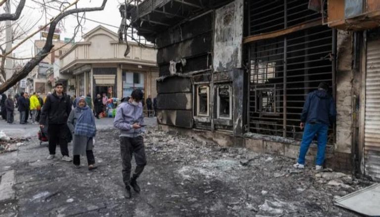 شاب يمر بجوار مبنى تدمر في الاحتجاجات