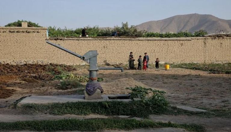 أطفال يقفون بالقرب من مضخة مياه يدوية جافة وسط أزمة مياه في كابول (رويترز)