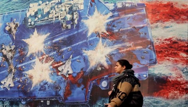 سيدة تمر بجوارة لوحة لحاملة طائرات في طهران