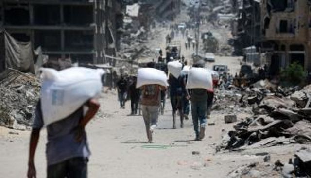 فلسطينيون يحملوا أكياسا من الدقيق على أكتافهم