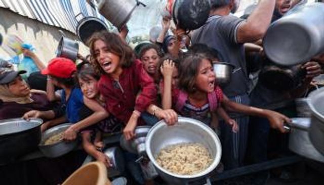 فلسطينيون يتدافعون لتلقي وجبة ساخنة من مطبخ خيري في مخيم النصيرات بغزة