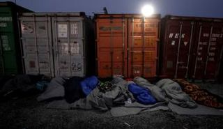 مهاجرون ينامون بجوار حاويات بالقرب من الحدود المقدونية اليونانية - رويترز