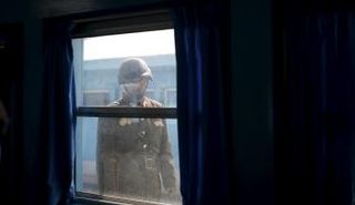 جندي كوري شمالي ينظر إلى داخل غرفة على الحدود مع كوريا الجنوبية (رويترز)