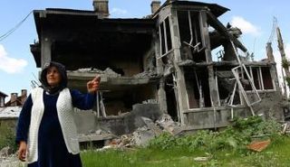امرأة تقف امام منزل دمر جراء الاشتباكات بين القوات التركية والأكراد في جنوب شرق تركيا - رويترز