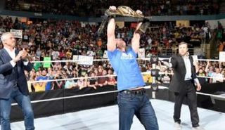 دين أمبروز يحمل حزام البطولة وبجانبه شين ماكمان ودانيال براين