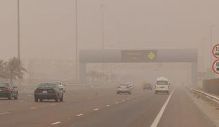 مركبات تعبر من تحت لوحة تحمل عبارة تحث على القيادة بحذر