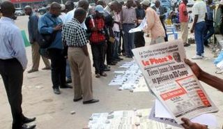 مواطنون يقرأون عناوين الصحف لدى بائع للصحف في كينشاسا