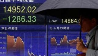 رجل يمر بشاشة تعرض مؤشر نيكي في طوكيو