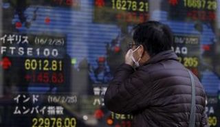 رجل يمر بلوحة تعرض مؤشرات الأسواق الآسيوية في طوكيو 