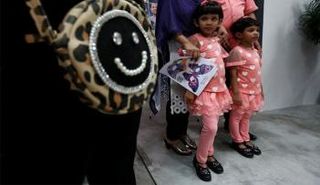 شقيقتان تحضران مع أبويهما عرضا فنيا للتوعية بشأن اللاجئين في هونج كونج - رويترز.