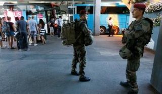 جنود فرنسيون يراقبون ركاب قبل ركوب حافلة في محطة حافلات في مدينة ليون