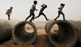 اطفال يلعبون فوق مواسير بموقع بناء في أحمد آباد بالهند