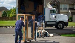 أشخاص ينقلون أغراضهم على متن سيارة لنقل الأثاث 