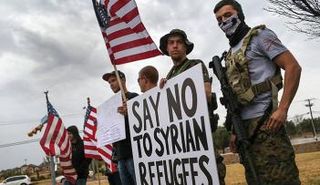 أحد المجموعات المسلحة في تكساس يحملون لافتة كتب عليها قل لا للاجئين السوريين