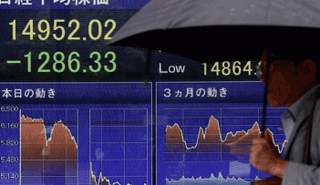 رجل يسير أمام شاشة تعرض مؤشر نيكي في طوكيو