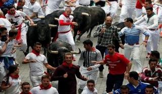 أشخاص يركضون أمام ثيران في مهرجان سان فيرمين في بامبلونا بشمال إسبانيا