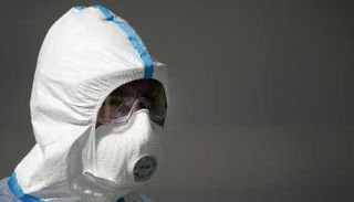 عامل يرتدي بذلة للحماية من المخاطر البيولوجية في مزرعة للدواجن 