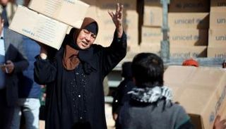 امرأة من النازحين تحمل مساعدات في مخيم للنازحين شمال الموصل