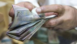 كويتي يحصي بعض العملات المحلية- أرشيف