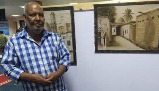 الفنان المصري أحمد مخيمر مع إحدى لوحاته