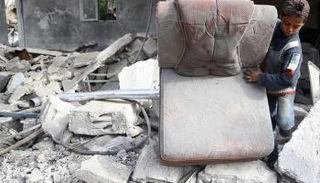 طفل سوري يبحث عن بقايا أثاث منزله تحت الحطام - رويترز